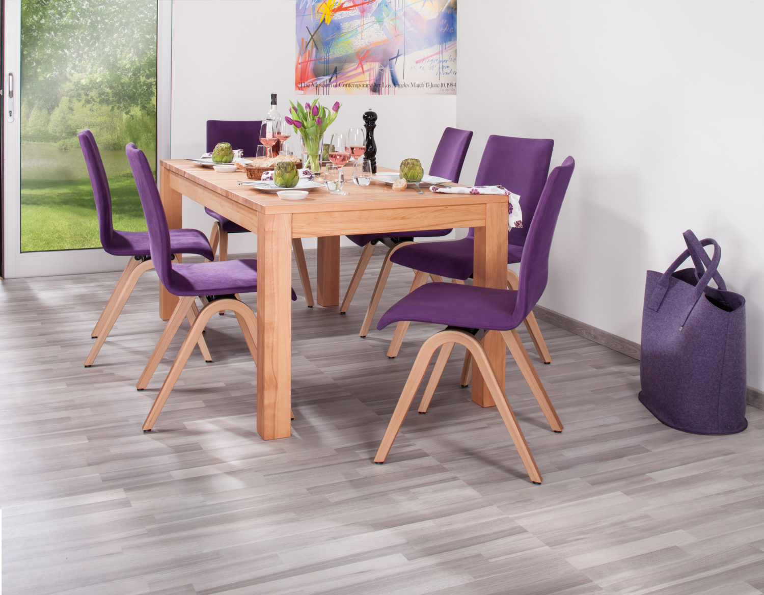 MOIZI Bewegungsstühle aus Holz an einem Esstisch in einem hellen Wohnraum